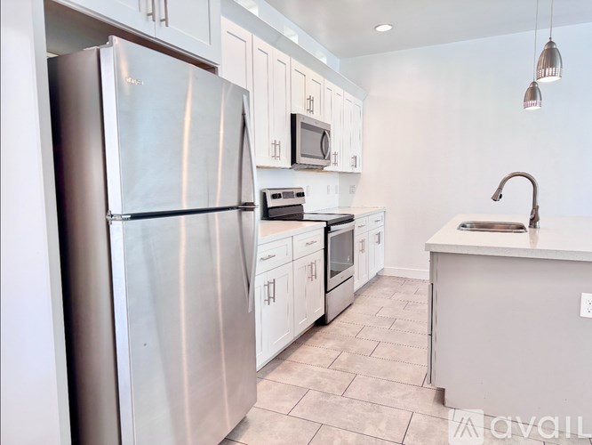 A kitchen with a refrigerator, microwave, oven, and sink.