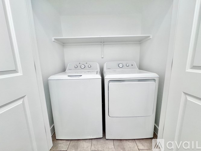 Two white front loading washing machines in a small laundry room.