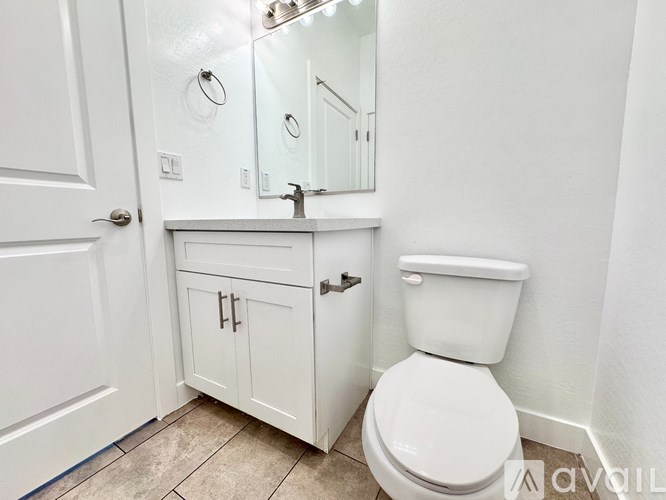 A white toilet in a small bathroom with a cabinet and mirror.