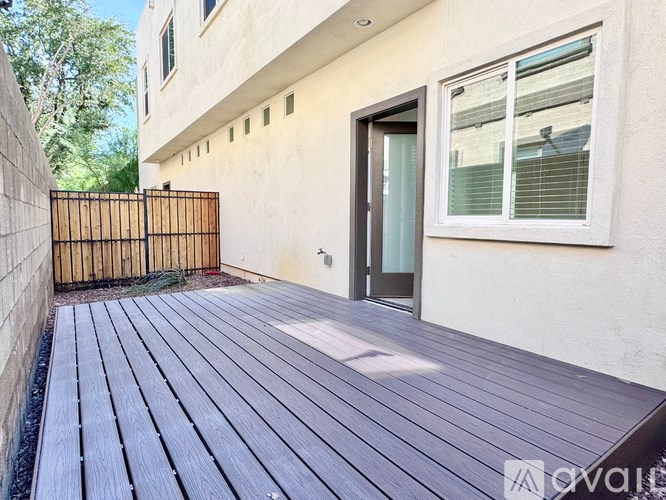 A wooden deck leads to a house with a black gate.