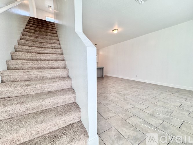 A staircase with beige carpeted steps leads up to a white wall.