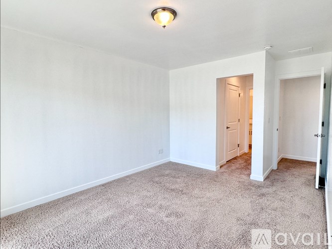 A carpeted room with a doorway leading to another room.