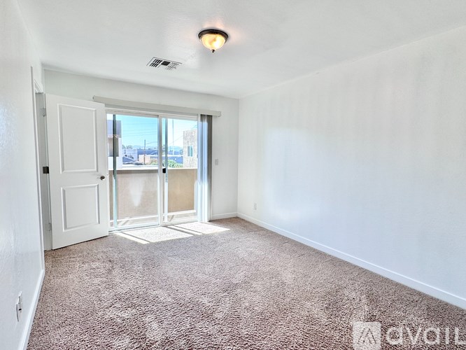 A room with a carpeted floor and a door leading to a balcony.