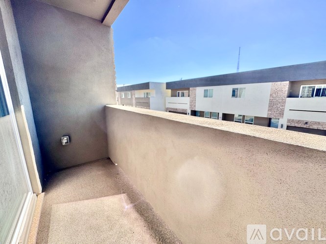 A balcony with a beige carpet and a wall with a small square window.