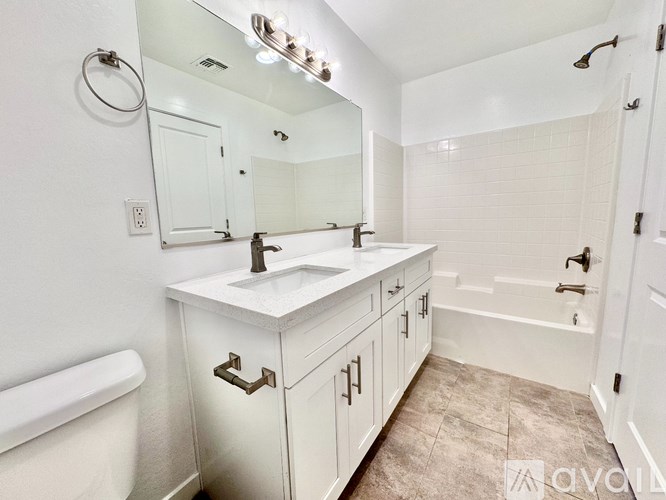 A white bathroom with a vanity, sink, and tub.