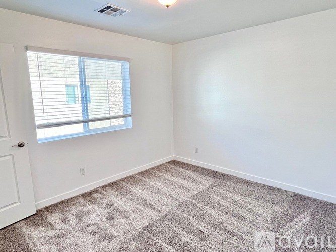 A room with a carpeted floor and a window with blinds.