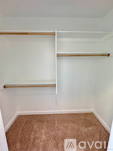 A room with a carpeted floor and two white shelves.