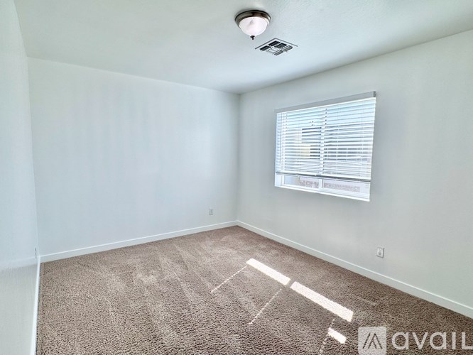 A room with a carpeted floor and a window with blinds.