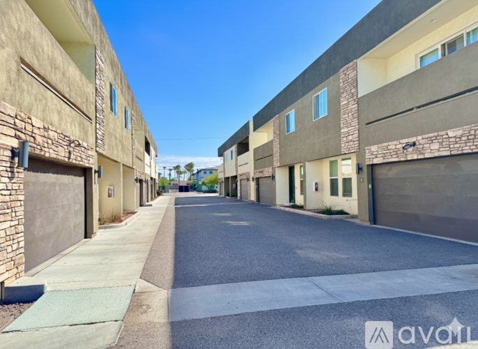 A street view of a residential area with buildings on both sides and a clear blue sky.