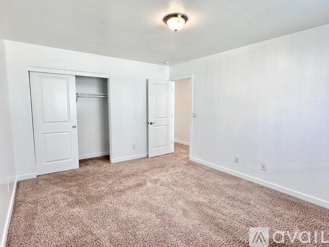 A carpeted room with a door and a window.