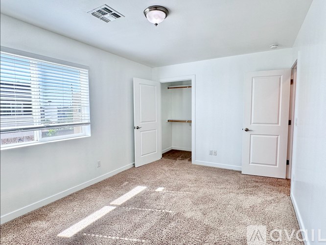 A room with a carpet on the floor and a window with blinds.