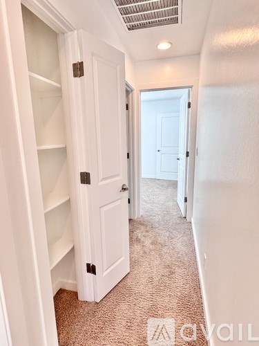 A hallway with a white door and carpeted floor.