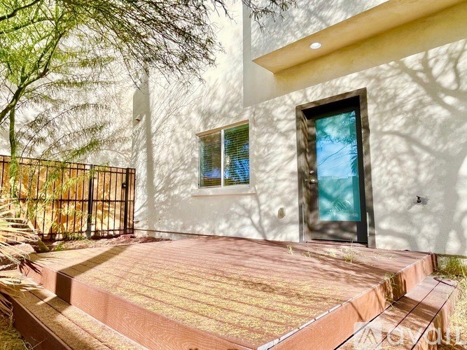 A white house with a black gate and a wooden deck.