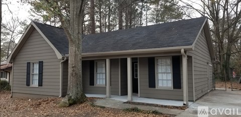 A small house with a grey roof and a porch.