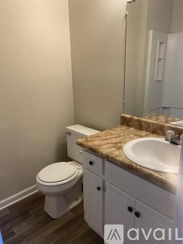 A bathroom with a toilet, sink, and a counter top.