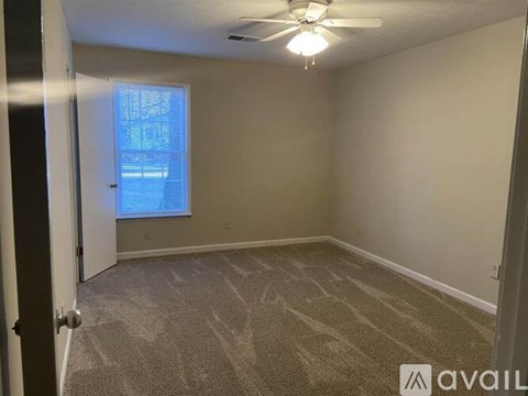 A room with a carpeted floor and a ceiling fan.