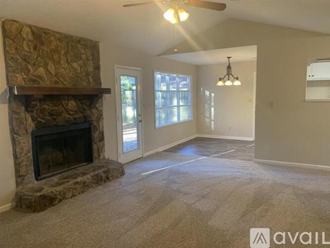 A living room with a stone fireplace and a carpeted floor.
