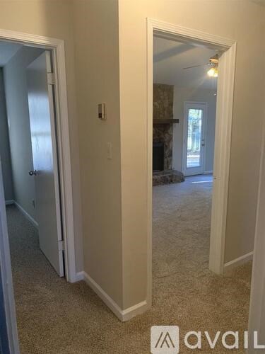 A hallway with a carpeted floor and a doorway leading to another room.