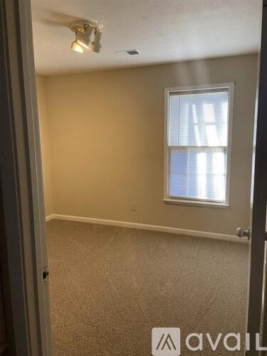 A room with a carpeted floor and a window with blinds.