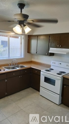 A kitchen with a white stove top oven and a fan ceiling light.
