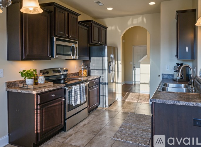A kitchen with dark brown cabinets and a granite countertop.