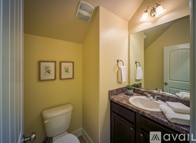 A bathroom with a toilet, sink, and mirror.
