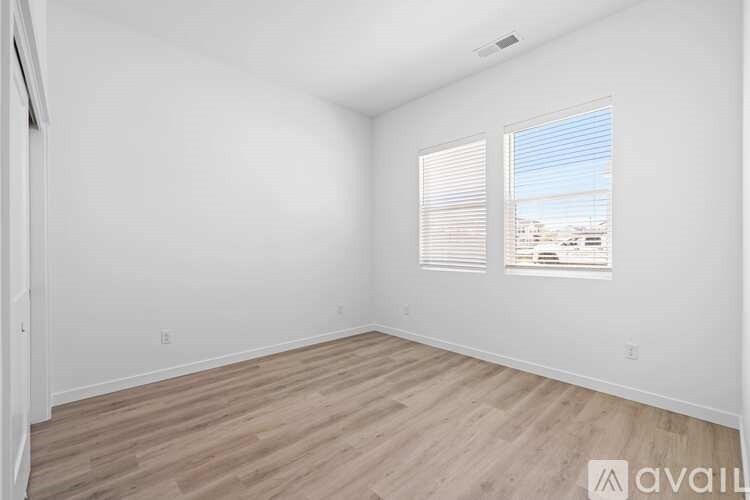 A room with wooden flooring and a window with blinds.