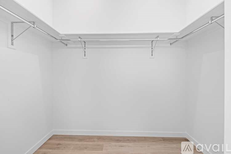 A white wall with a wooden floor and a metal pipe running along the wall.