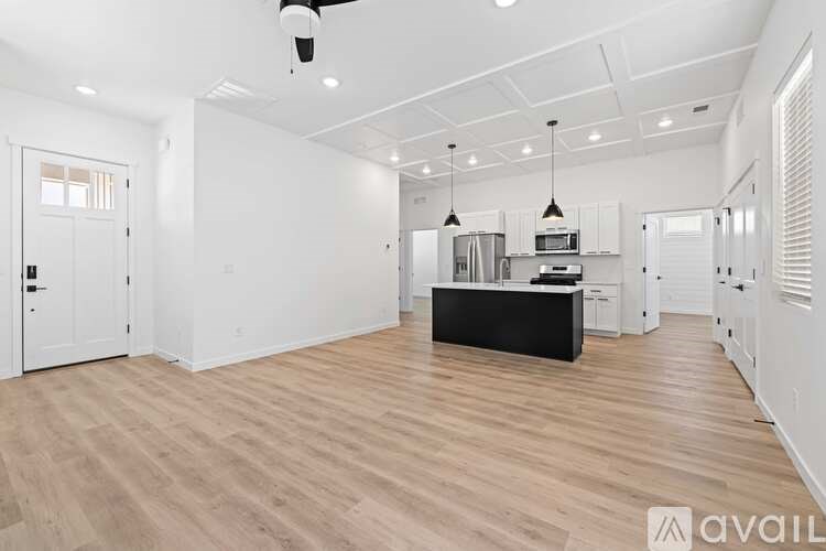 A spacious kitchen with wooden flooring and white walls.