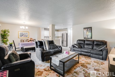 A living room with black leather furniture and a floral rug.