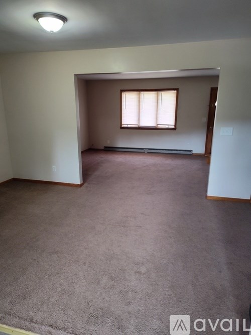 A room with a carpeted floor and a window with blinds.