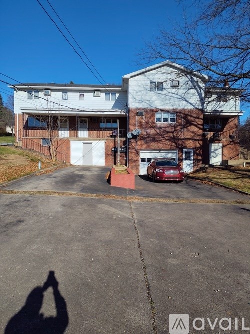 A two-story building with a garage and a car parked in front.