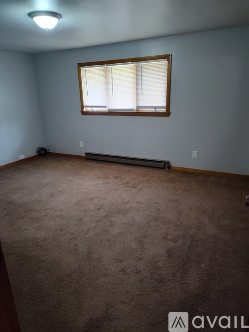 A room with a carpeted floor and a window with blinds.