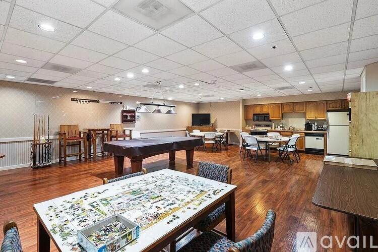 A large room with a puzzle on the table and chairs around it.