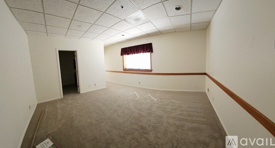 A room with a carpeted floor and a window with red curtains.