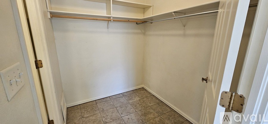A white closet with a shelf and a tiled floor.