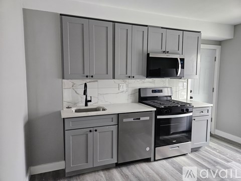 A kitchen with grey cabinets and stainless steel appliances.