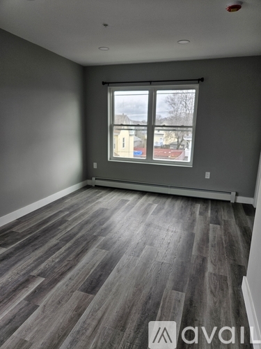 A room with grey walls and a large window with a view of a residential area.