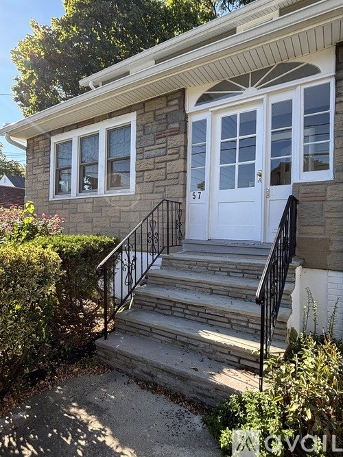 A house with a white door and a black railing on the stairs.