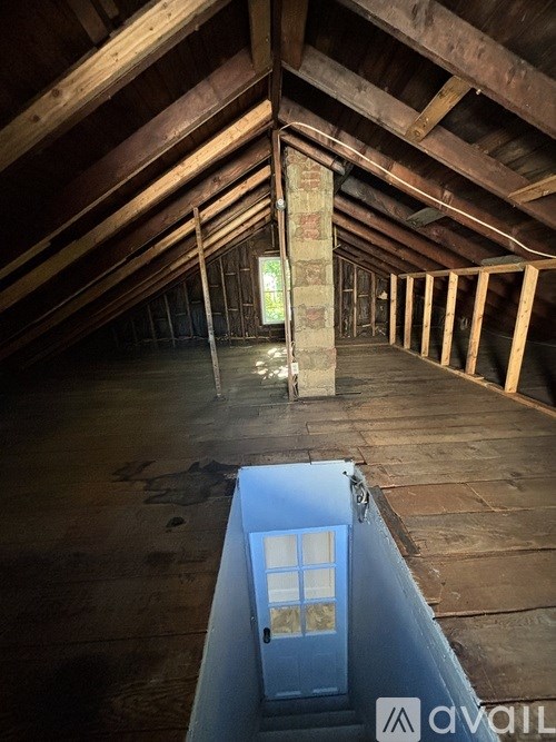 A view of a room with wooden floors and ceiling, a window, and a wall with a sign that says "AVAIL".