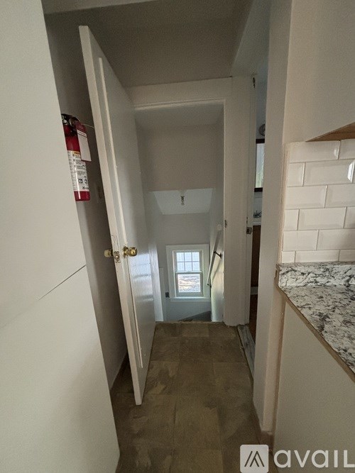 A hallway with a door on the left and a window on the right.