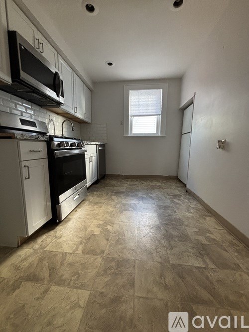 A kitchen with tile flooring and white cabinets.