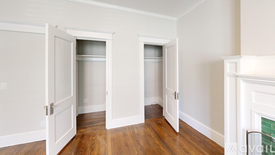 A room with two open doors and a fireplace on the right side.