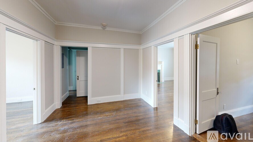 A room with wooden floors and white walls, with a door on the right side.