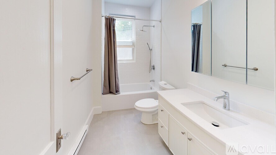 A white bathroom with a toilet, sink, and shower.
