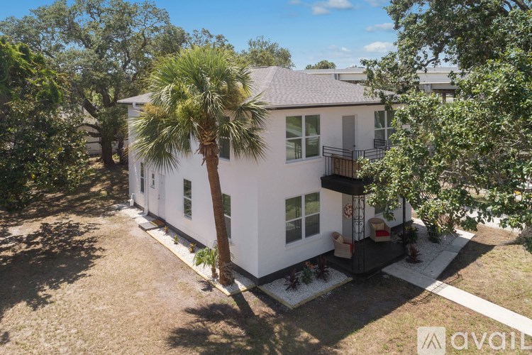 A white house with a balcony and a palm tree in front.