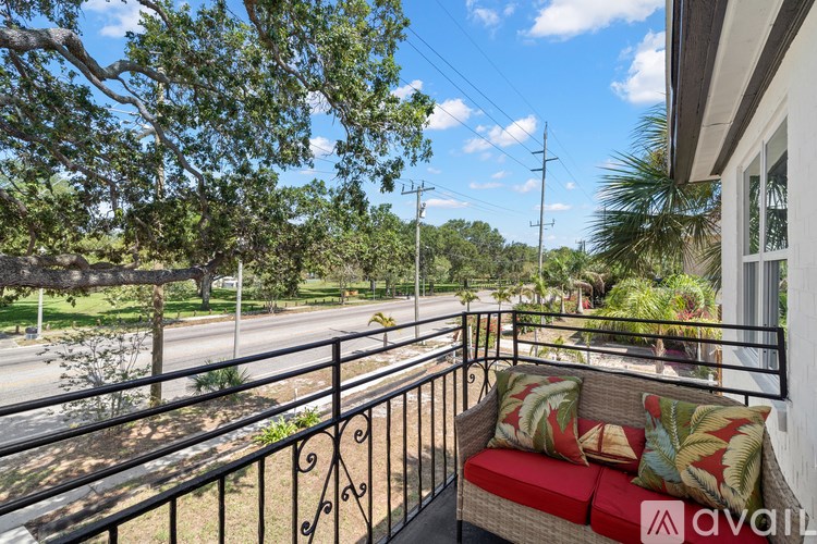 A balcony with a red couch and a view of a street with trees.