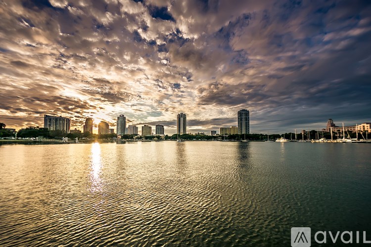 A city skyline is reflected in the water at sunset.