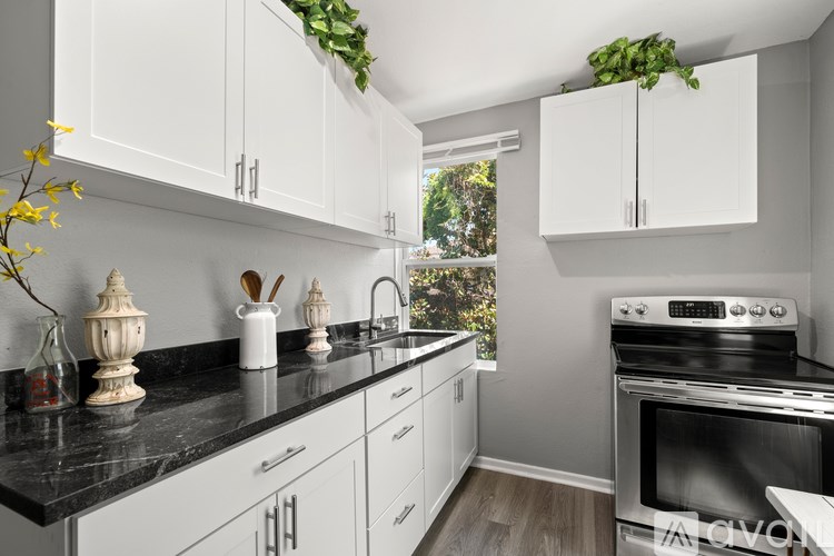 A kitchen with white cabinets and a black countertop.