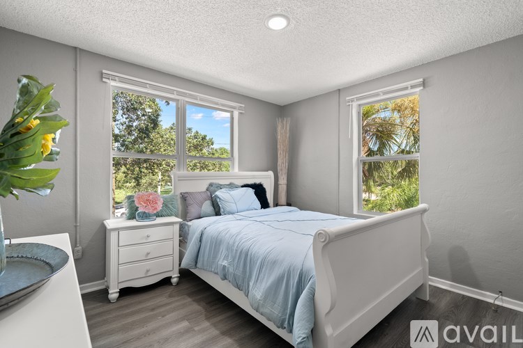A bedroom with a bed, nightstand, and window.